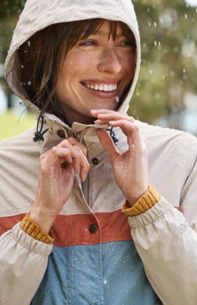 A woman is zipping up a jacket in the rain. The scene captures a moment of preparation and resilience against the weather.