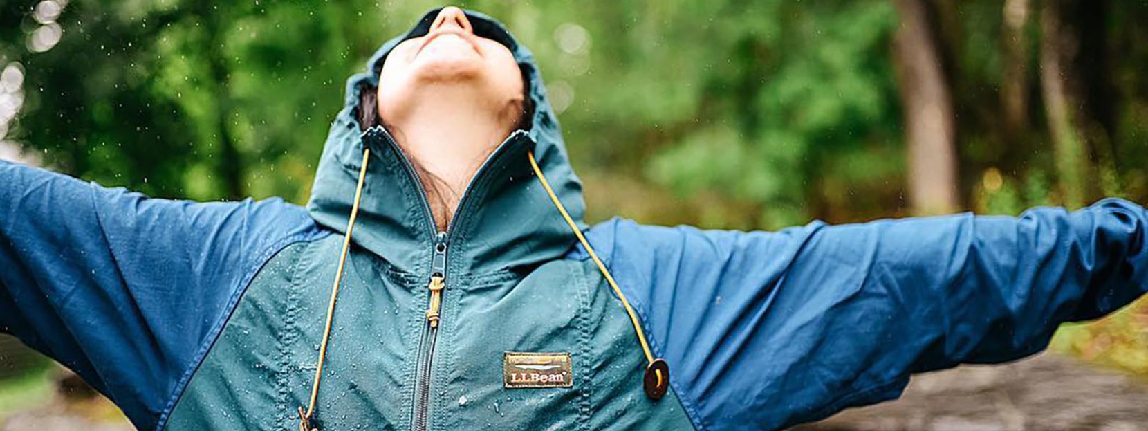 A person standing with arms spread and face up-lifted to the sky while it is raining.