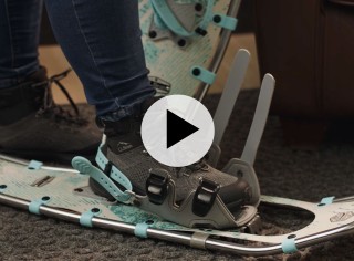 Close-up of foot of someone putting on a snowshoe.