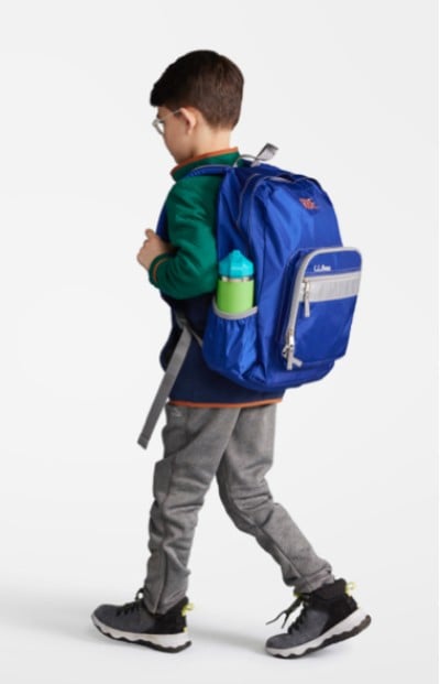 Young boy wearing a blue school backpack.