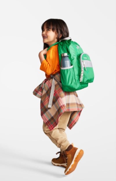 Young girl wearing a green school backpack.