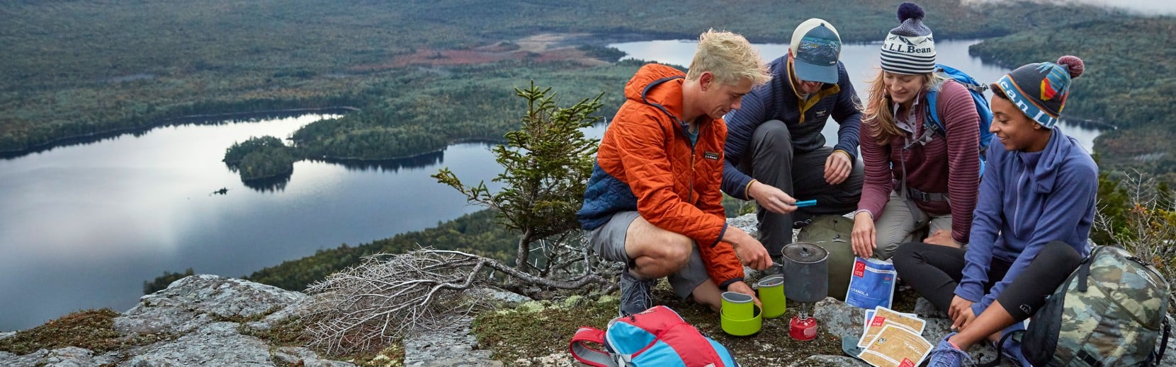 A group of friends on a mountain top cooking after a hike.