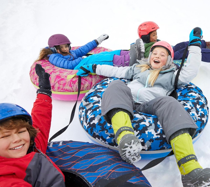 4 laughing kids sledding on Sonic Snow Tubes.