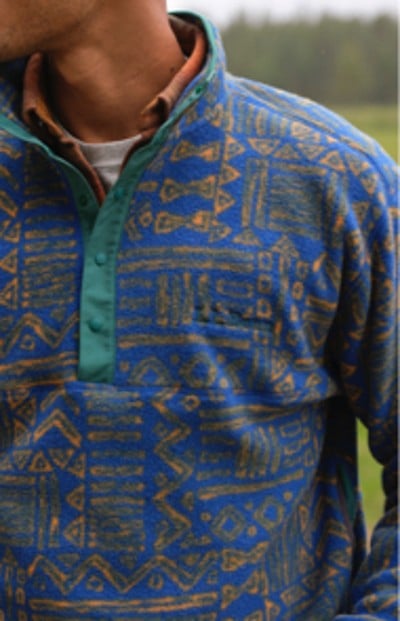 A close-up of a person wearing a patterned blue, cozy fleece top.