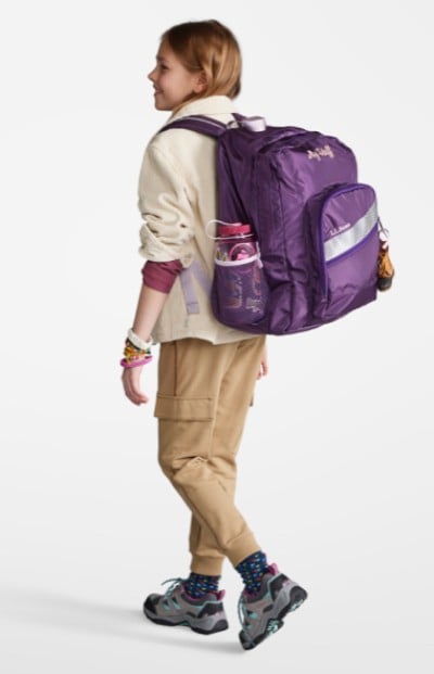 Young woman wearing a purple school backpack.