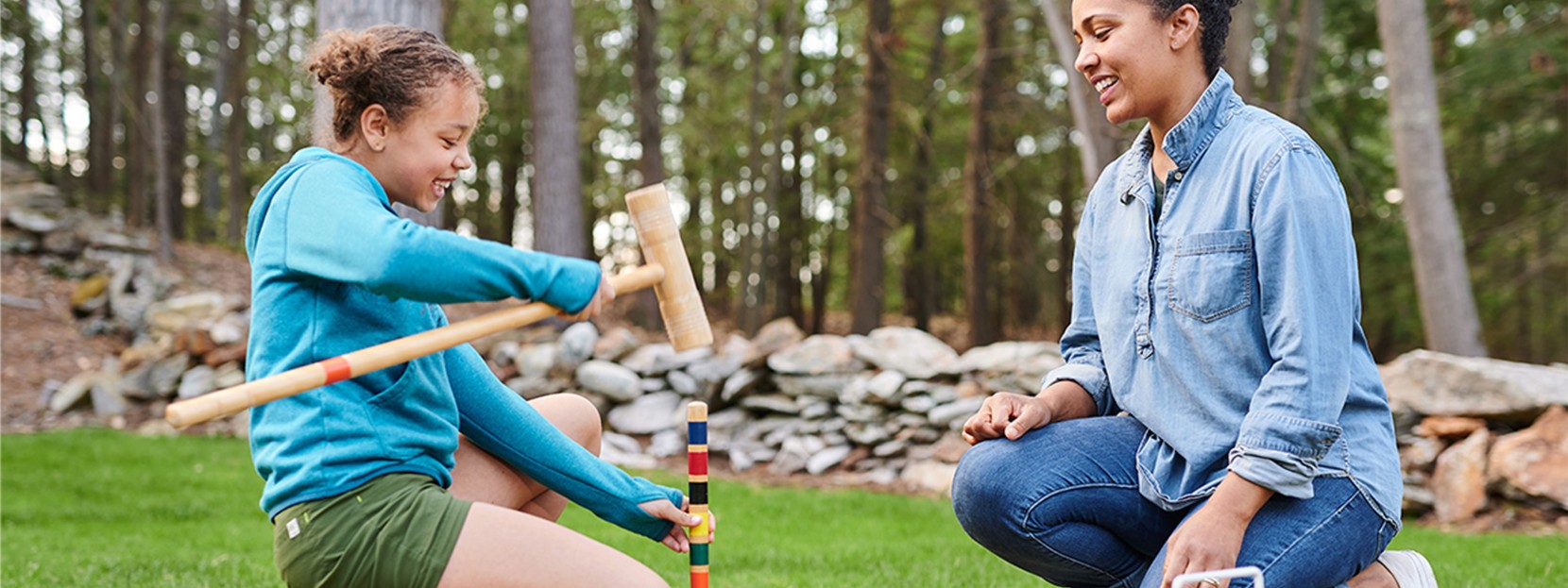 Mom an daughter kneeling down in green grass, setting up an L.L.Bean croquet set.