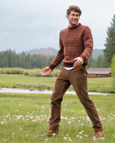 Man outside in a field wearing a Ragg Wool Sweater.