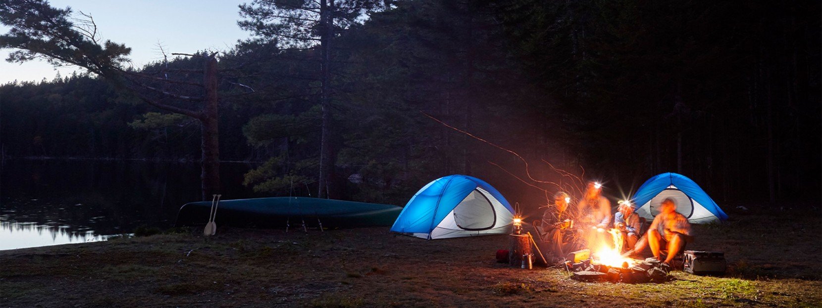 Family gathered around a campfire at night.