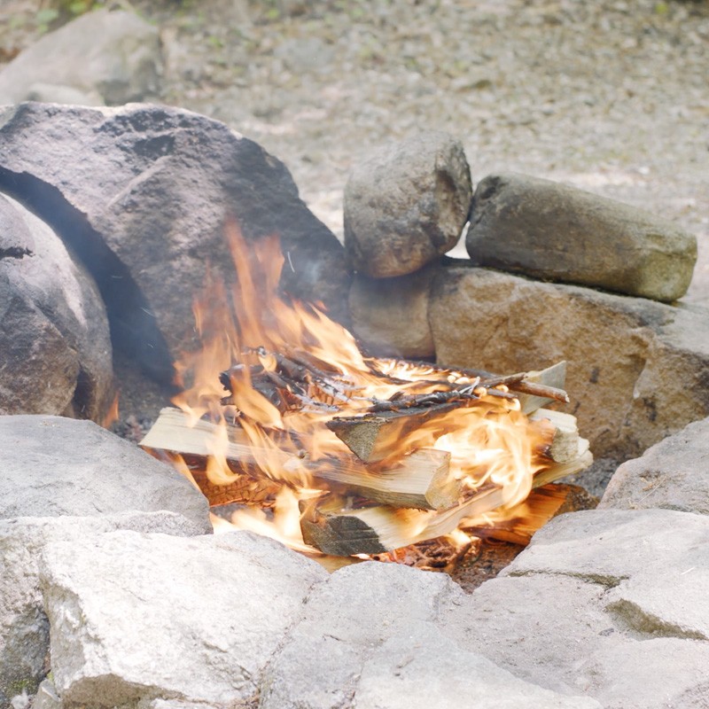 Nate adding tinder to the first layer of logs, filling the gaps between logs.