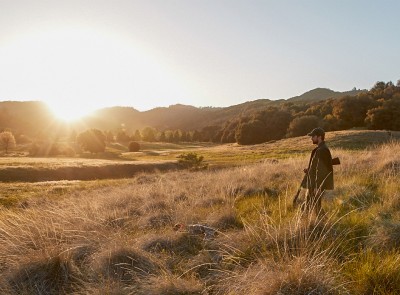 Hunter standing in a field at sunset.