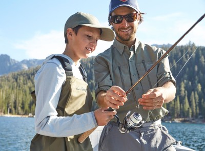 Son and father looking at spin fishing rod.