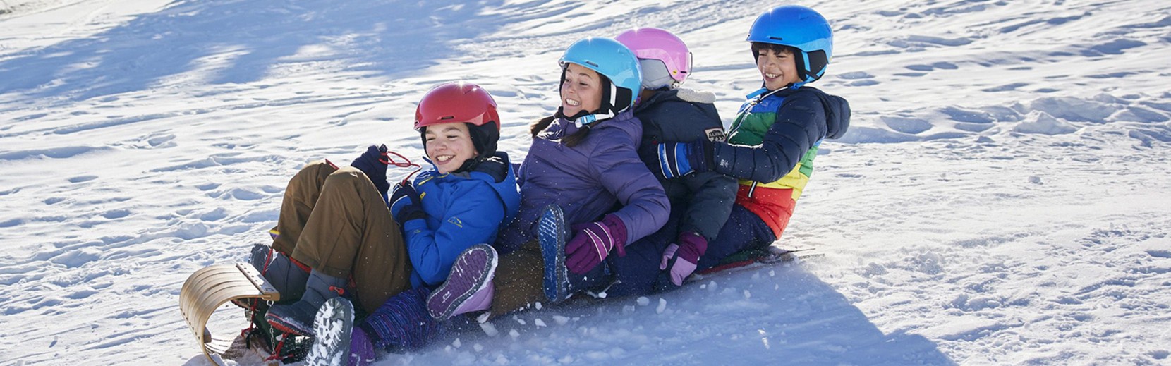 Four kids sledding on snow tubes.