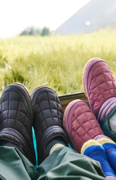 Two people are reclining with their feet up in a field, showcasing a moment of relaxation and connection with nature.