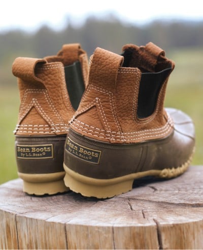 A pair of Bean Boots outside on a stump.