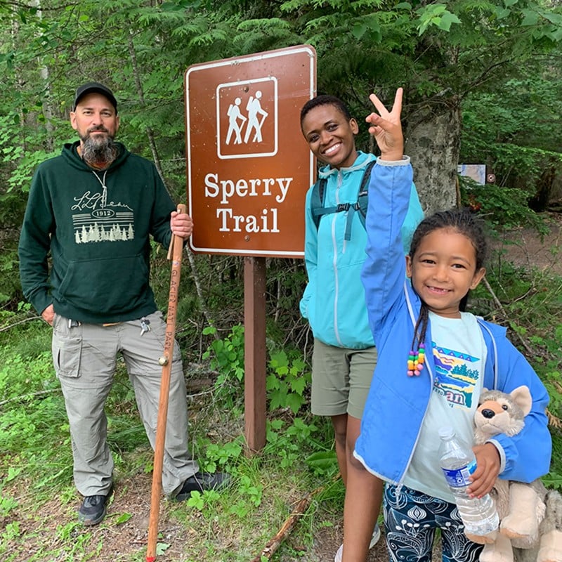 Dineo Dowd and family by a trailhead sign, getting ready for a hike.