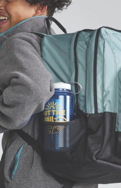 Close-up of a water bottle in the outer pocket of a school backpack.