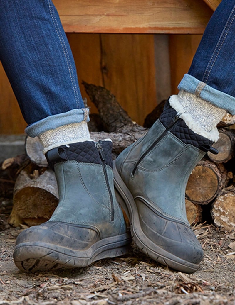 Close-up of boots on feet, person sitting on a bench outside.