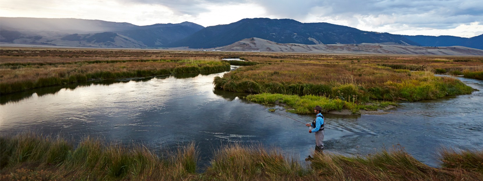 Man standing in a river fishing.