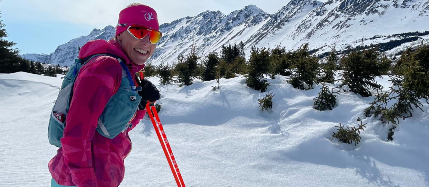 L.L.Bean Ambassador Kikkan Randall outside on cross-country skis, a beautiful mountain range in the background.