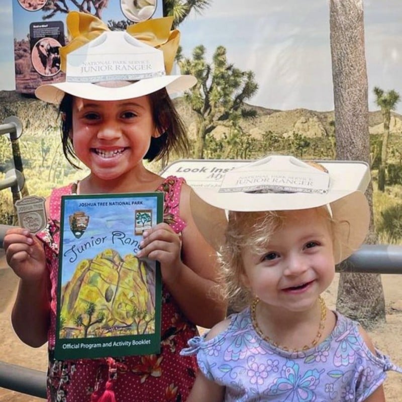 Two children smiling with their Junior Ranger badge and activity book.