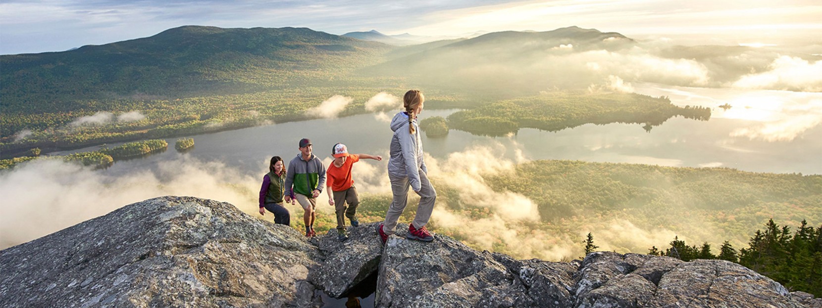 Family of 4 enjoying a beautiful sunrise view on a mountaintop.