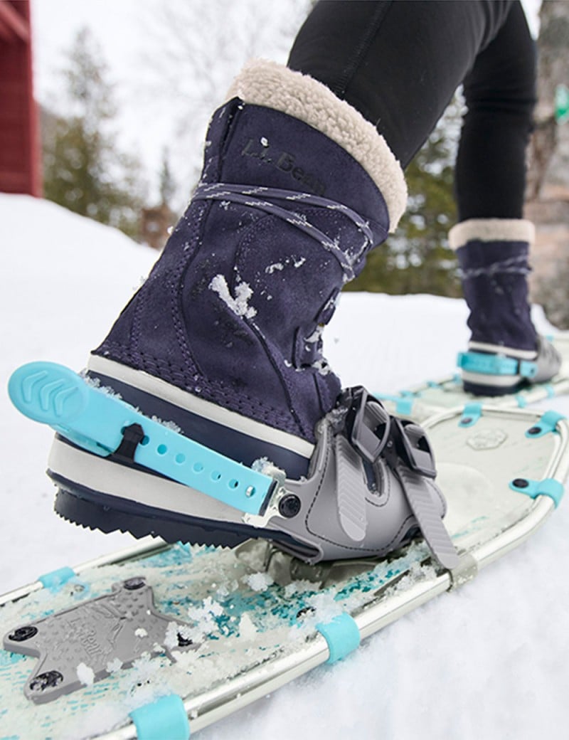 Close-up of boots and snowshoes on feet, walking on the snow.